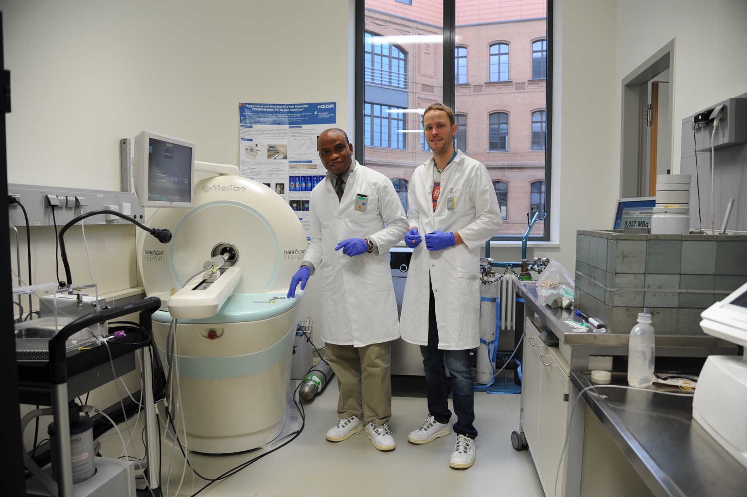 Dr Philip Njemanze and a research collaborator beside PET/MRI equipment.